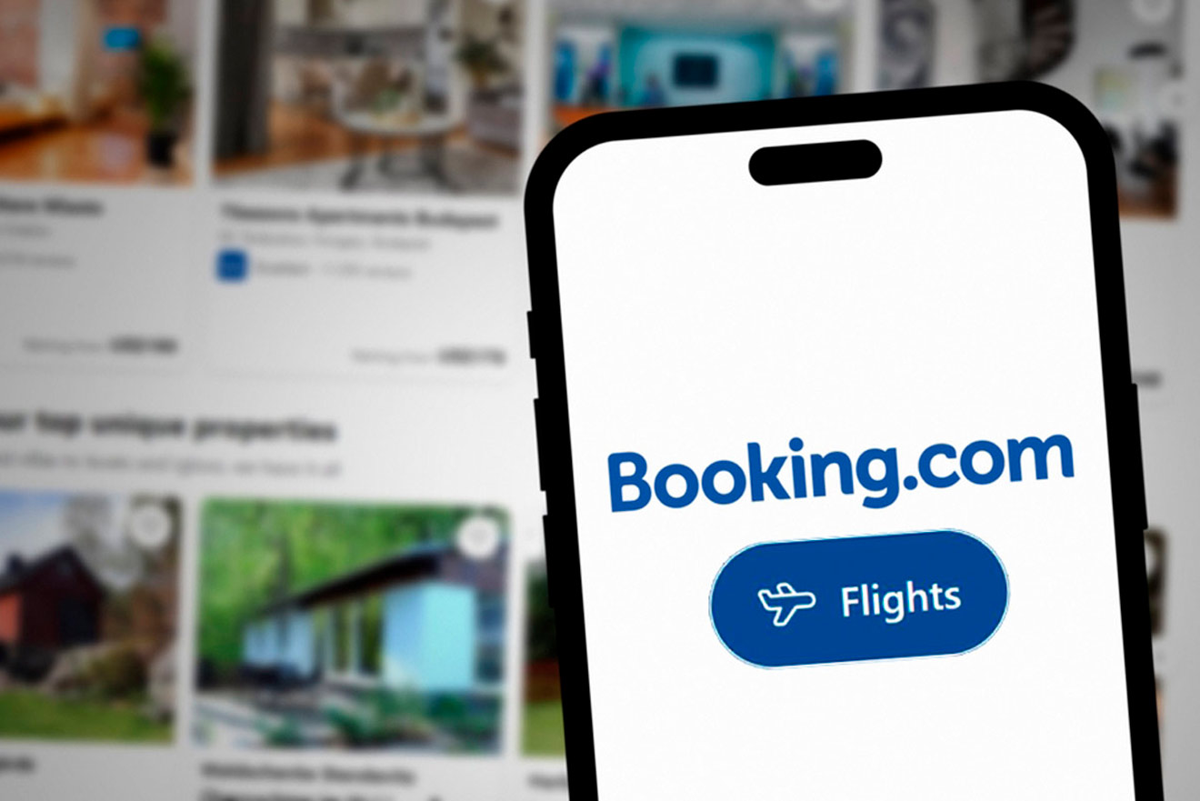 Phone screen displaying "Booking.com" and "Flights" against a blurred background of property listings.