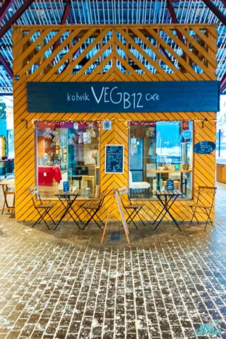 Front view of Kohvik VEGB12 café with a colorful exterior, small outdoor seating, and a chalkboard menu.