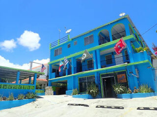 A bright blue and green building with multiple flags displayed outside, under a clear blue sky.