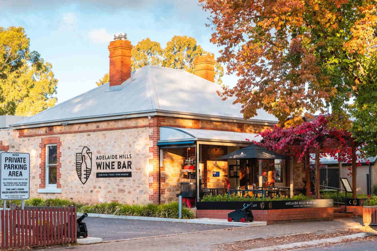 A charming wine bar in a brick building with a tree displaying autumn foliage nearby, and a private parking area sign on the fence.