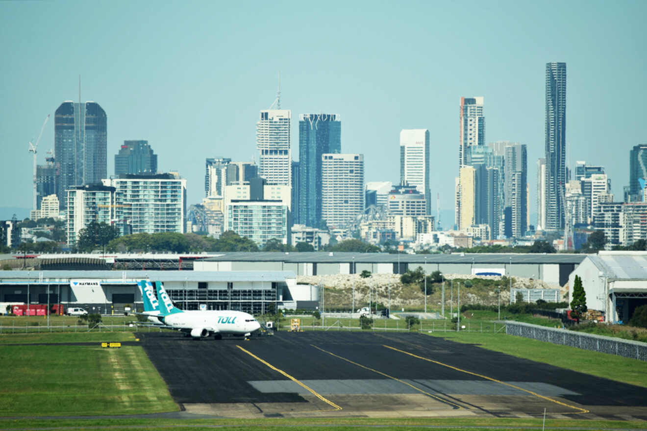 Airplane on a runway with a city skyline in the background.