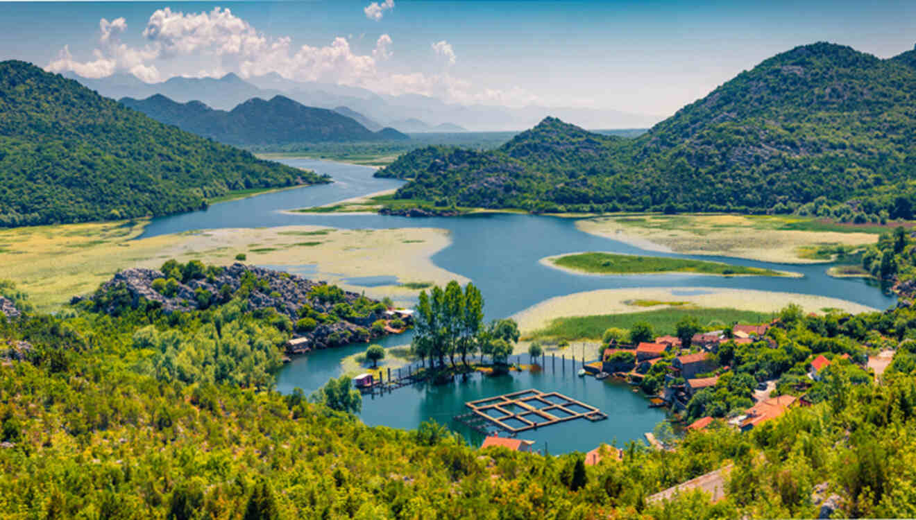 A scenic view of Lake Skadar with surrounding green hills, a small village, and a fish farm in Montenegro.