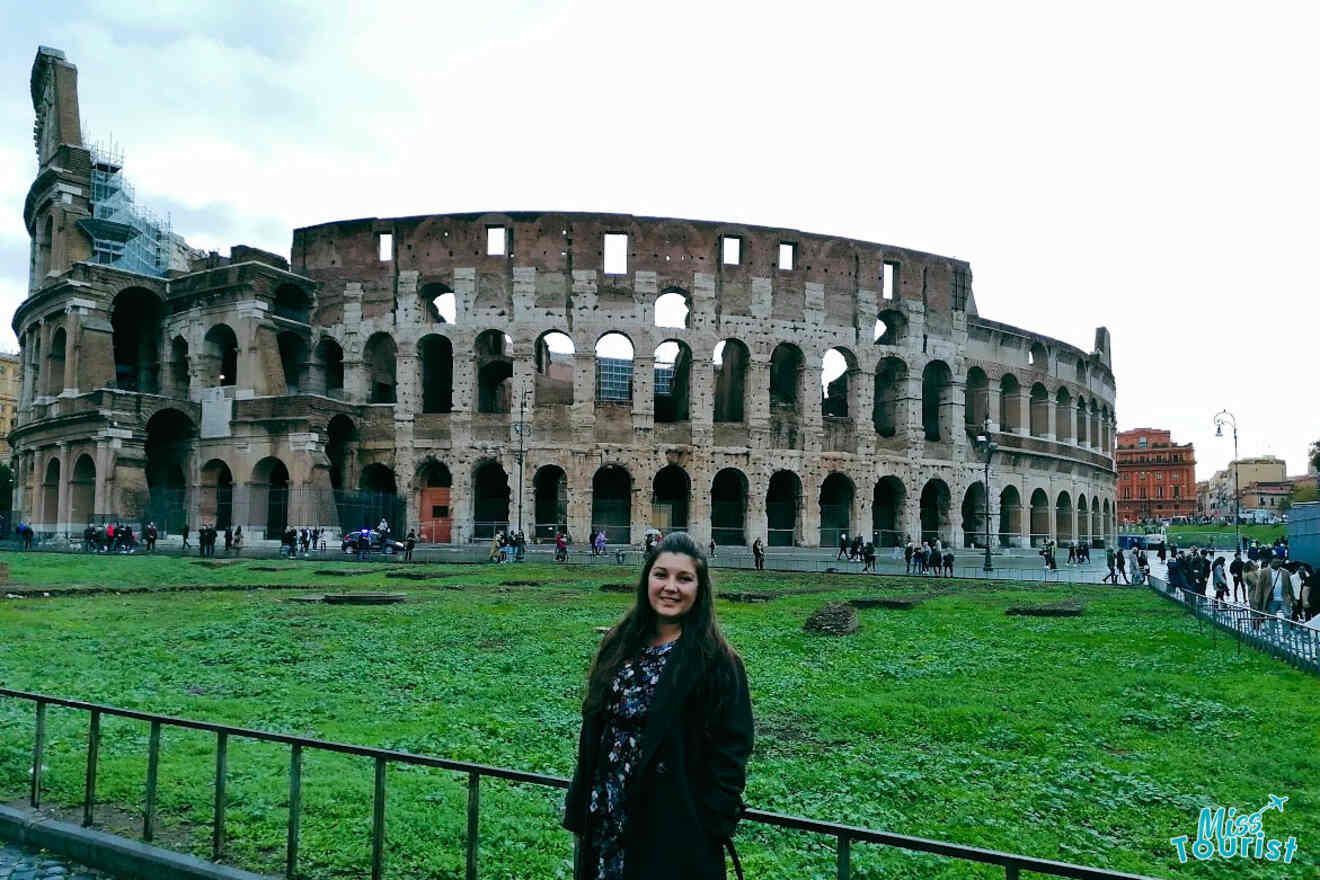 A person stands in front of the Colosseum in Rome, Italy, on a cloudy day.