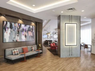 Modern hotel lobby with seating, contemporary artwork, and wooden flooring. Illuminated wall decor and mixed furniture styles create a welcoming ambiance.