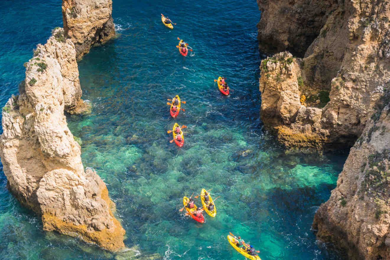 An aerial view of people kayaking in the crystal-clear blue waters of Lagos, Portugal, navigating gracefully between dramatic rocky formations.