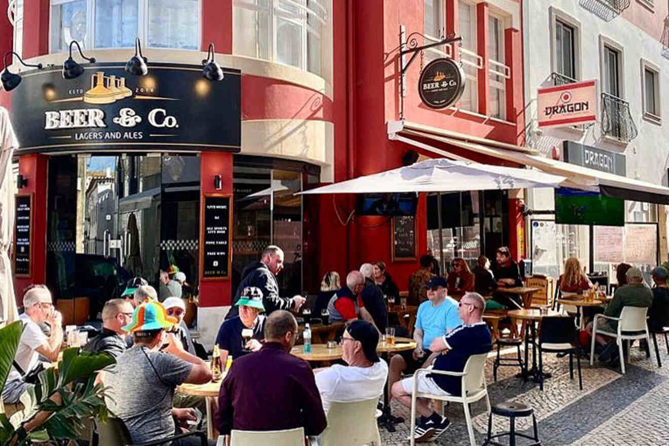 People are seated at outdoor tables of a bar named "Beer & Co." on a sunny day, with surrounding buildings and signage visible.