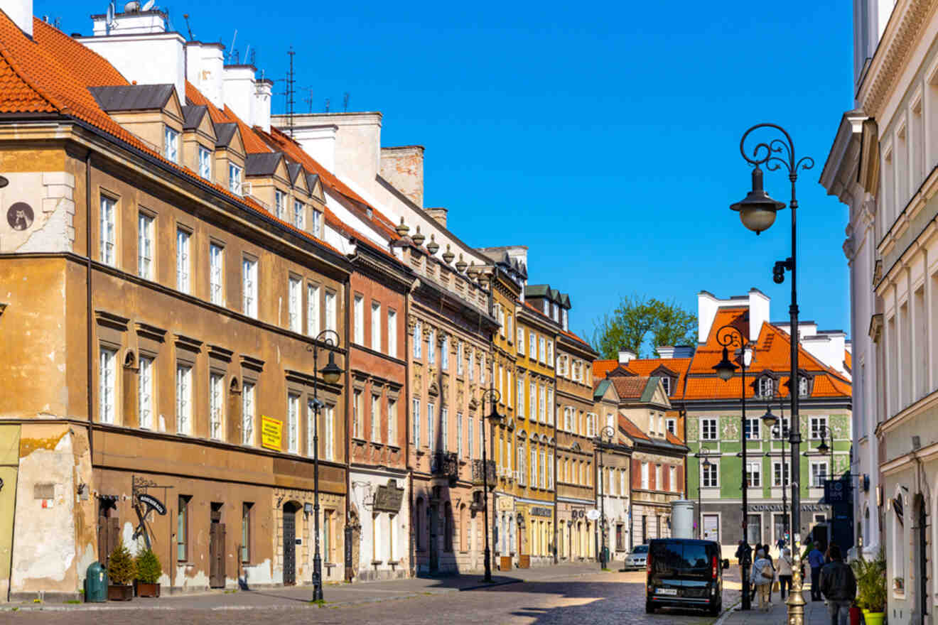 A sunny street in a European city with colorful historic buildings, a few pedestrians, and vintage street lamps.