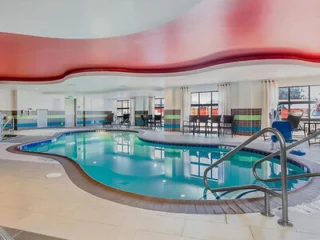 Indoor pool area with a curved ceiling, surrounded by windows and seating.