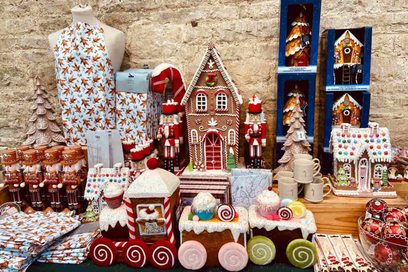 Display of gingerbread houses, cookies, and themed textiles arranged on a table against a brick wall.