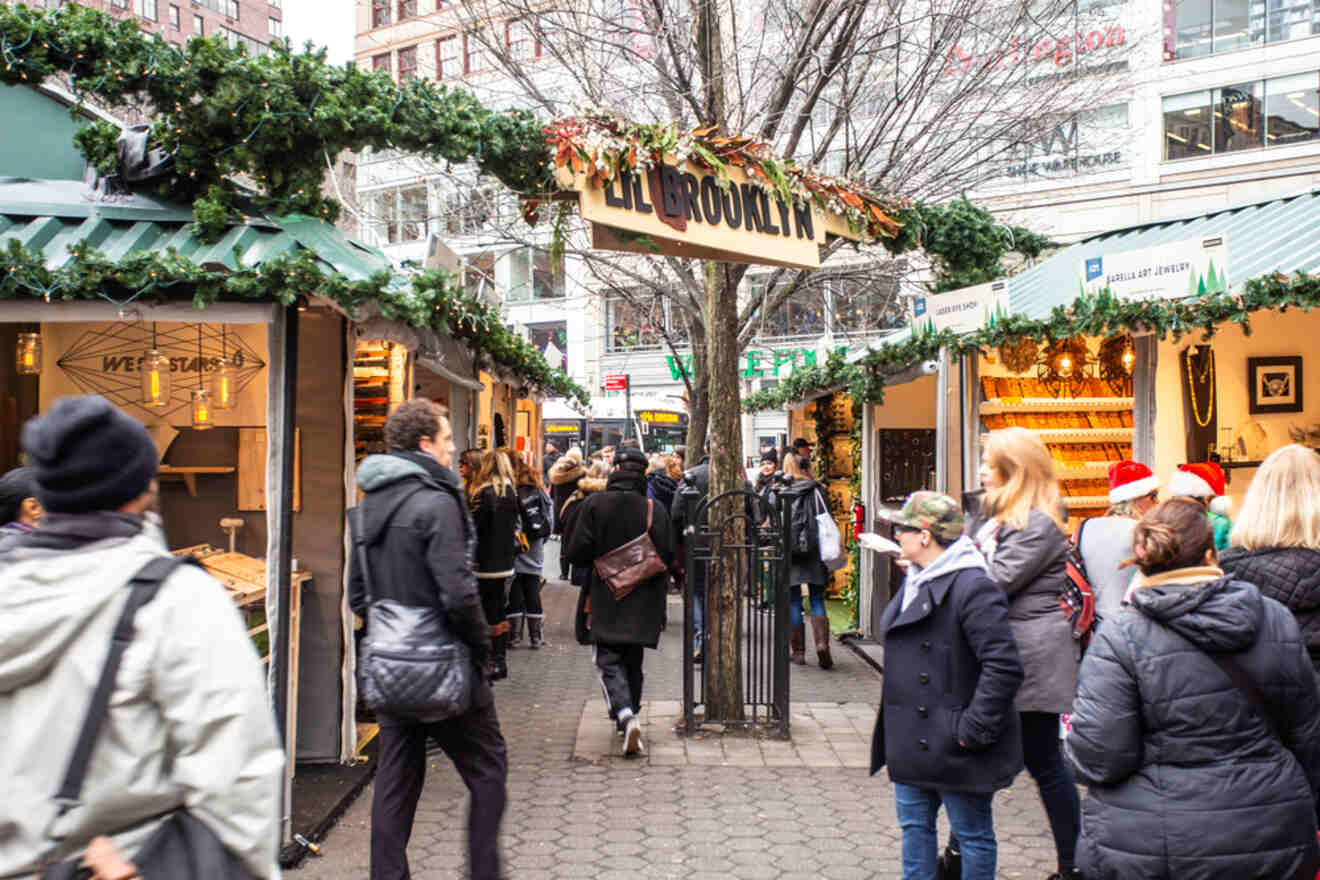 A busy outdoor market with people walking between stalls decorated with greenery. There is a sign overhead reading "All Brooklyn.