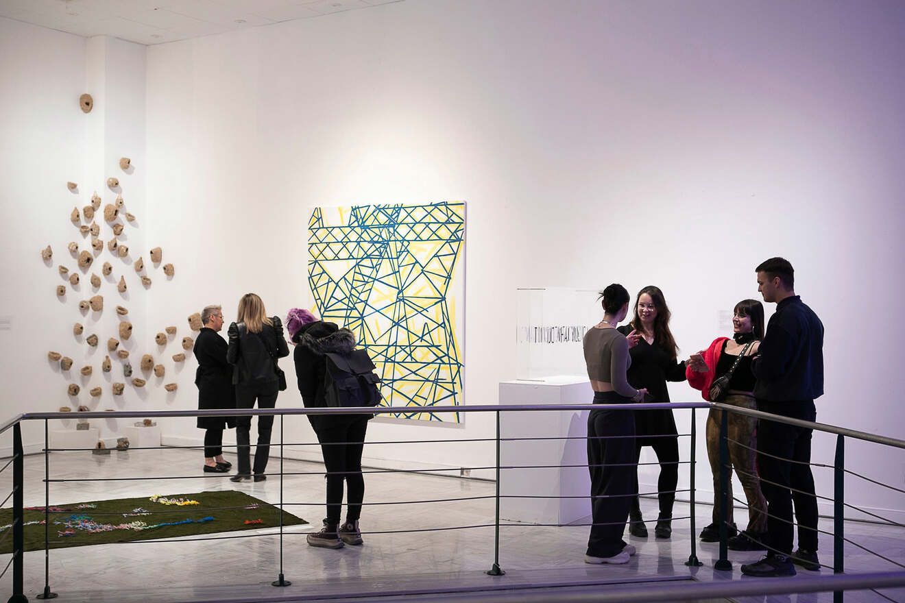 People viewing various artworks in a modern gallery setting.