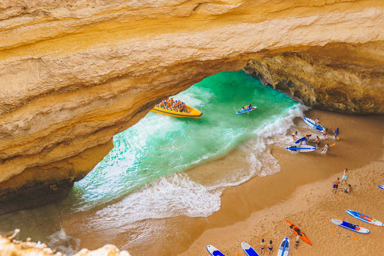 In Lagos, Portugal, people delight in paddleboarding and sunbathing inside a vast cave with turquoise water, while a boat carrying passengers glides through the cave's grand opening.