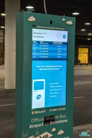 Digital display showing Aerobus schedules at Barcelona Airport. Includes routes to Pl. Catalunya and information on exchanging Hola Barcelona Travel Cards.