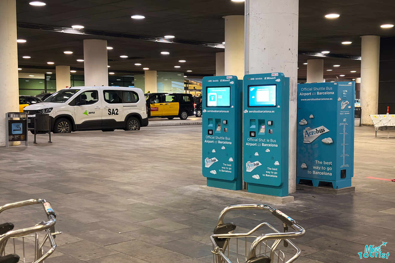 Airport shuttle kiosks and parked shuttle buses in a well-lit transportation area.