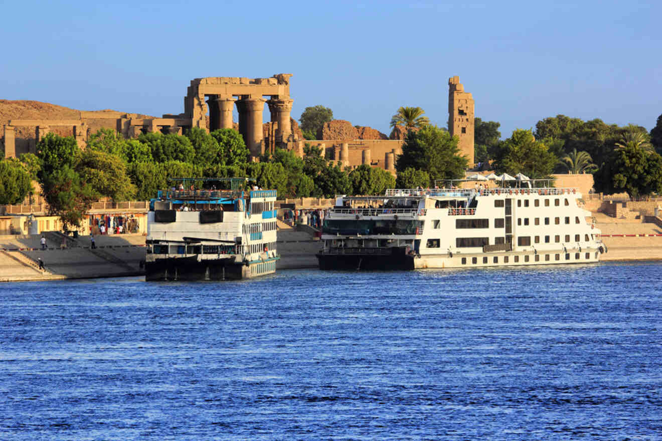 Cruise ships docked on the Nile River with ancient ruins and greenery in the background.