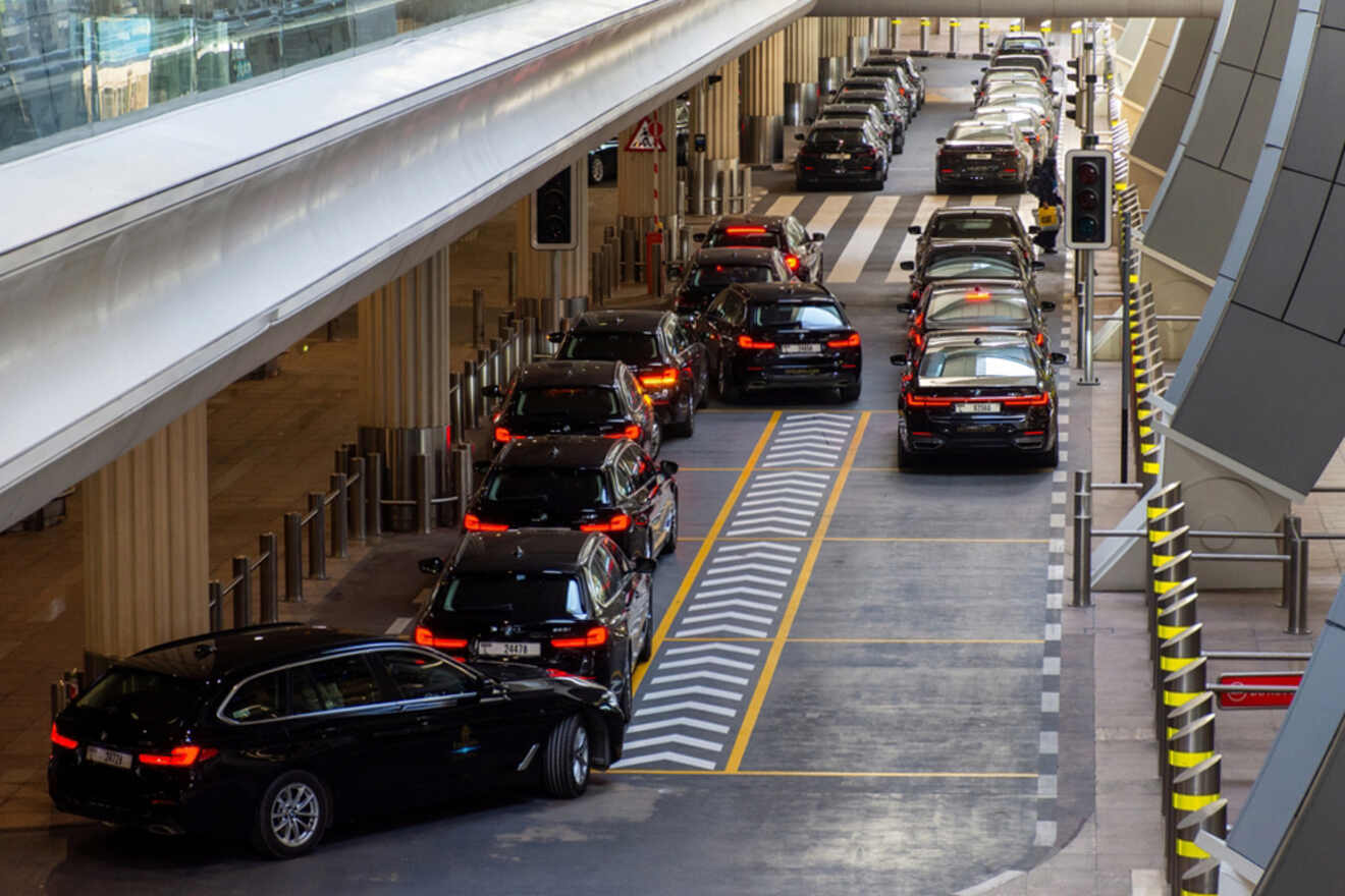 Cars lined up in a single file under a covered area, following a marked lane.