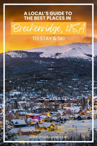 Scenic winter view of Breckenridge, USA with snow-covered houses and mountains at sunset, promoting a guide for places to stay and ski.