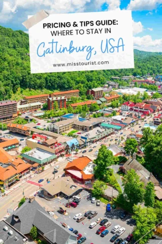 Aerial view of Gatlinburg, USA, featuring hotels, shops, and roads surrounded by lush green hills. Sign reads: "Pricing & Tips Guide: Where to Stay in Gatlinburg, USA.