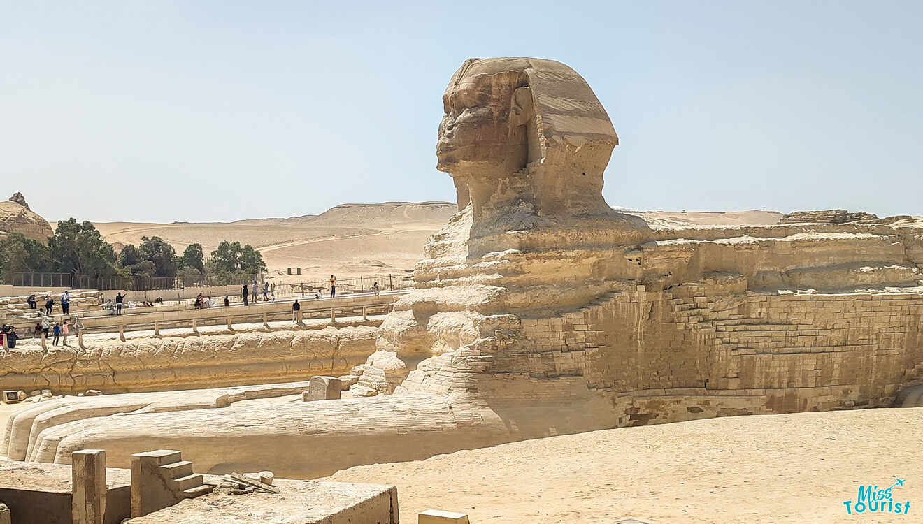 The Great Sphinx of Giza in Egypt, with tourists nearby, under a clear sky.