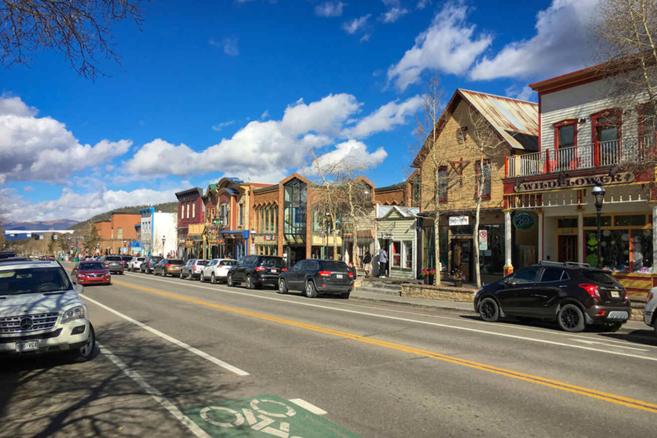 A small town street with parked cars and colorful historic buildings under a blue sky.