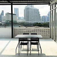 A minimalist patio with a table and four chairs overlooking a city skyline, featuring modern high-rise buildings under a clear sky.