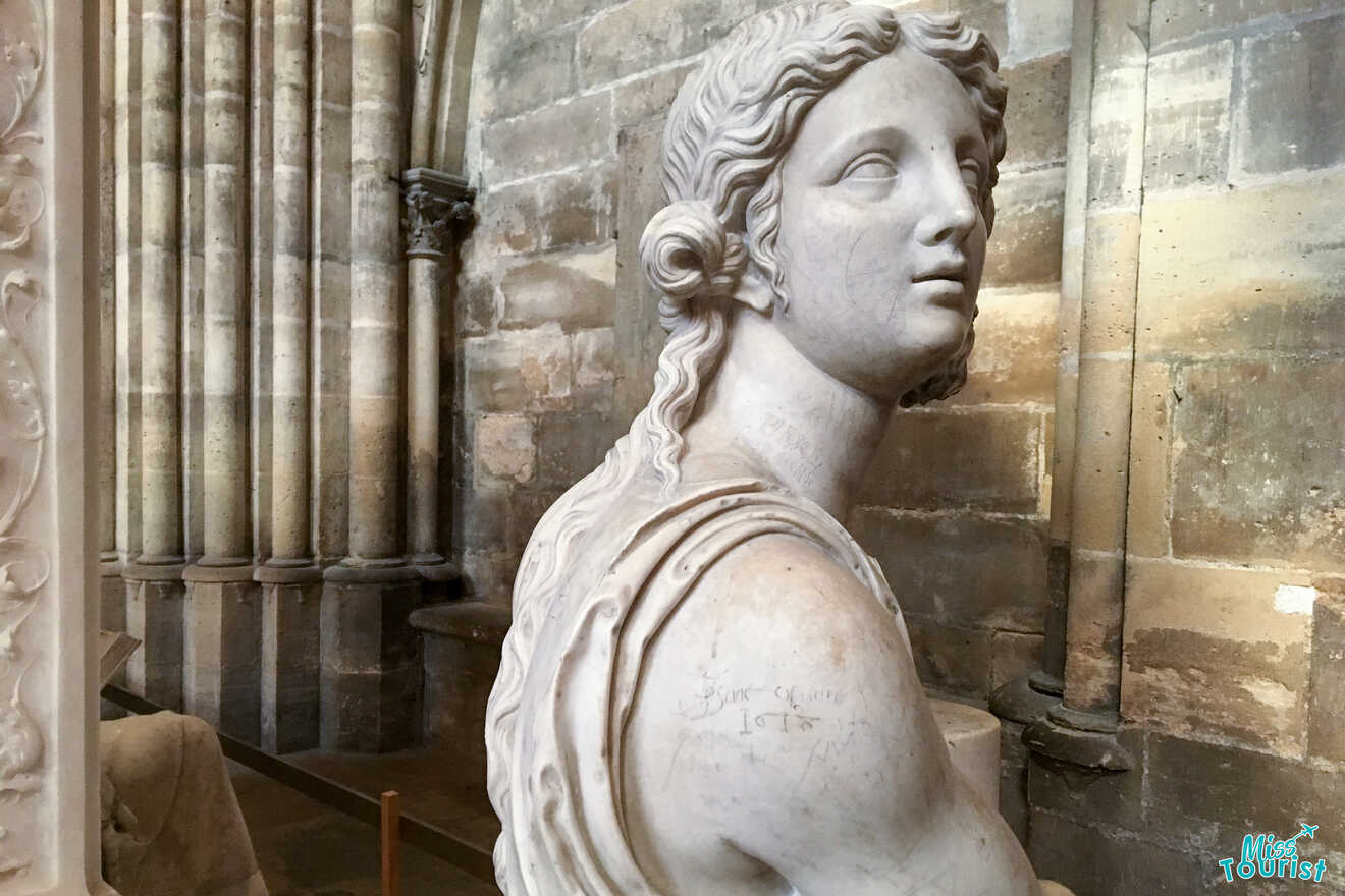 Marble statue of a woman in a historic stone building, with ornate columns visible in the background.