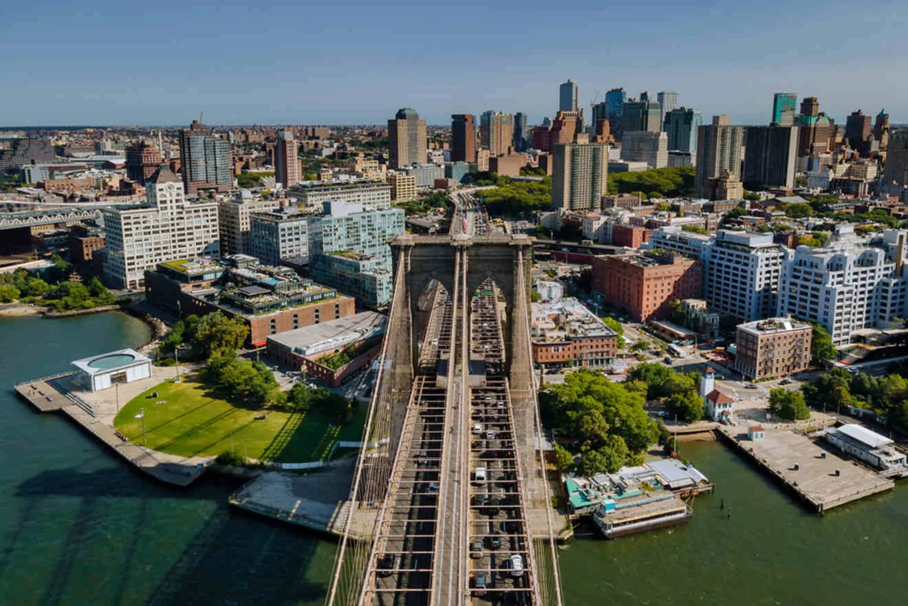 Aerial view of the Brooklyn Bridge spanning the East River, with Manhattan's skyline in the background on a clear day.