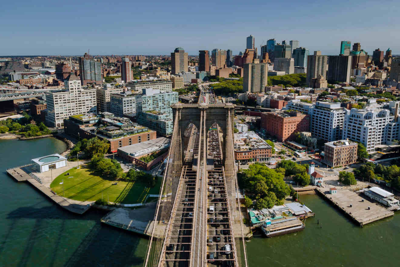 Aerial view of the Brooklyn Bridge spanning the East River, with Manhattan's skyline in the background on a clear day.