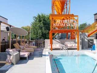 Outdoor pool area with lounge chairs and an orange metal structure labeled "Swim Club." Trees are visible in the background.