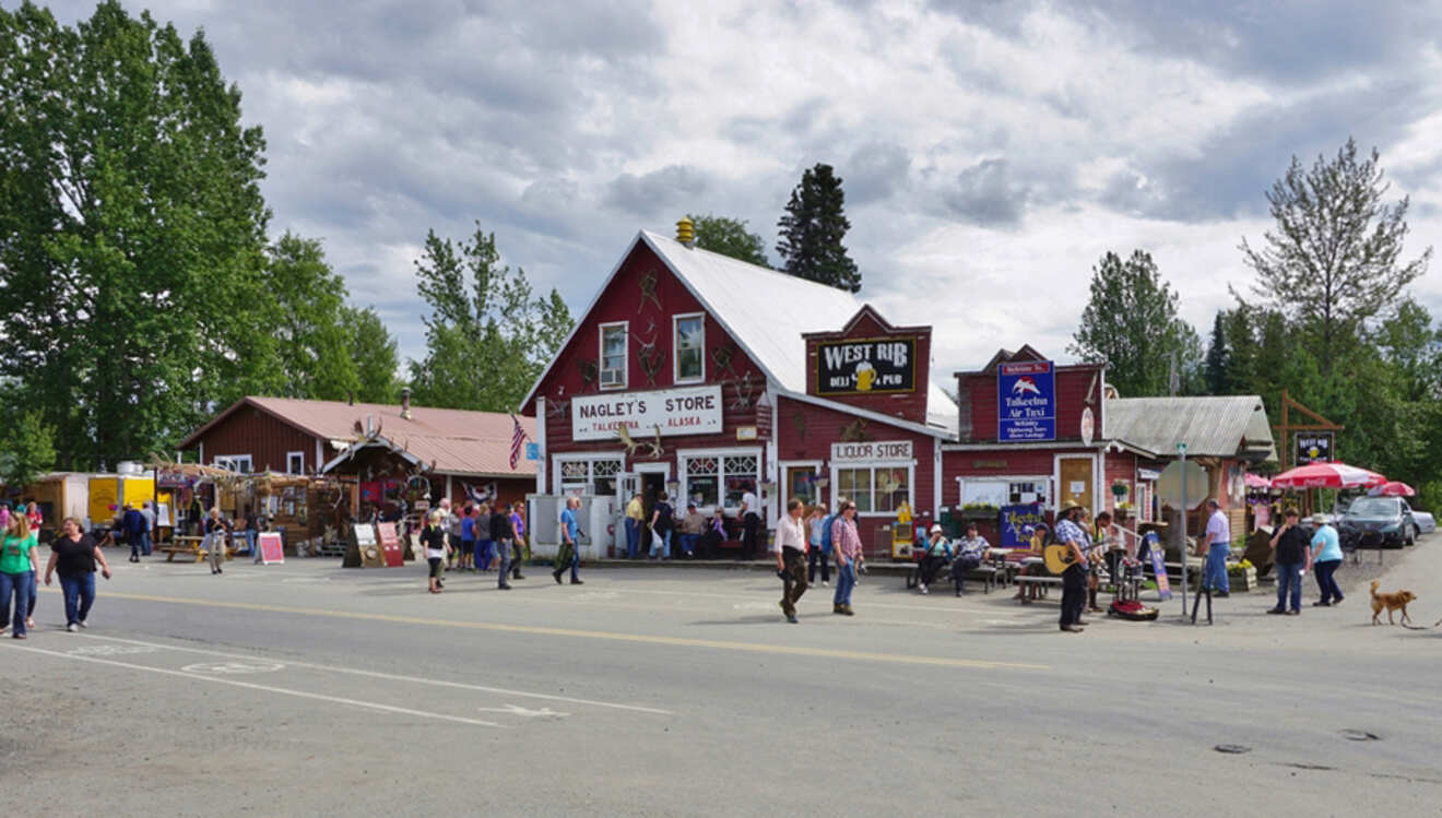 People walk near Nagley’s Store and West Rib Pub in a small town with overcast skies.