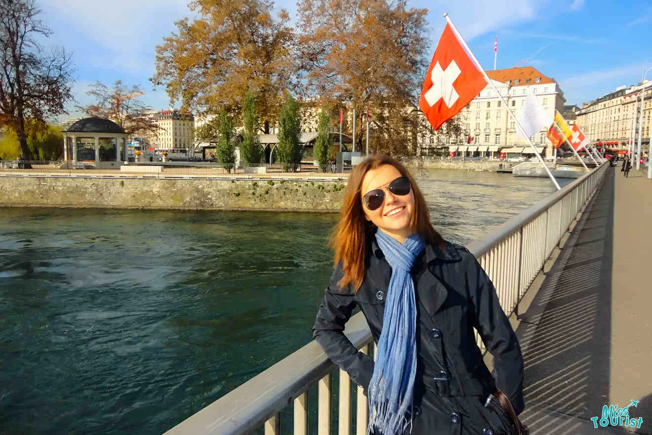 The writer of the post in a black coat and sunglasses smiles while standing on a bridge. Swiss flags are visible in the background in Geneva